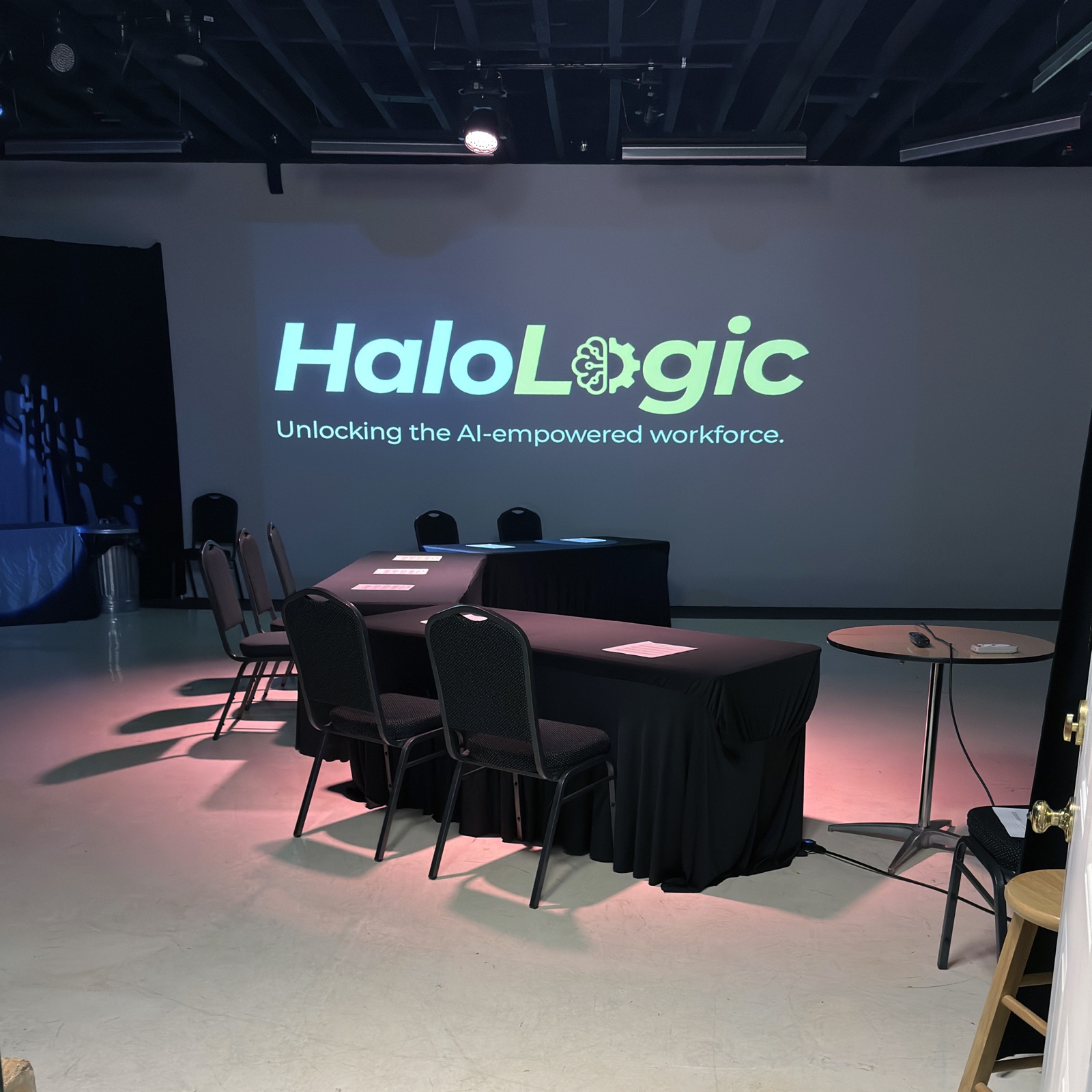The workshop room at Mailroom Studios set and empty before Session One, chairs and draped tables facing a wall-sized Halo Logic projection.